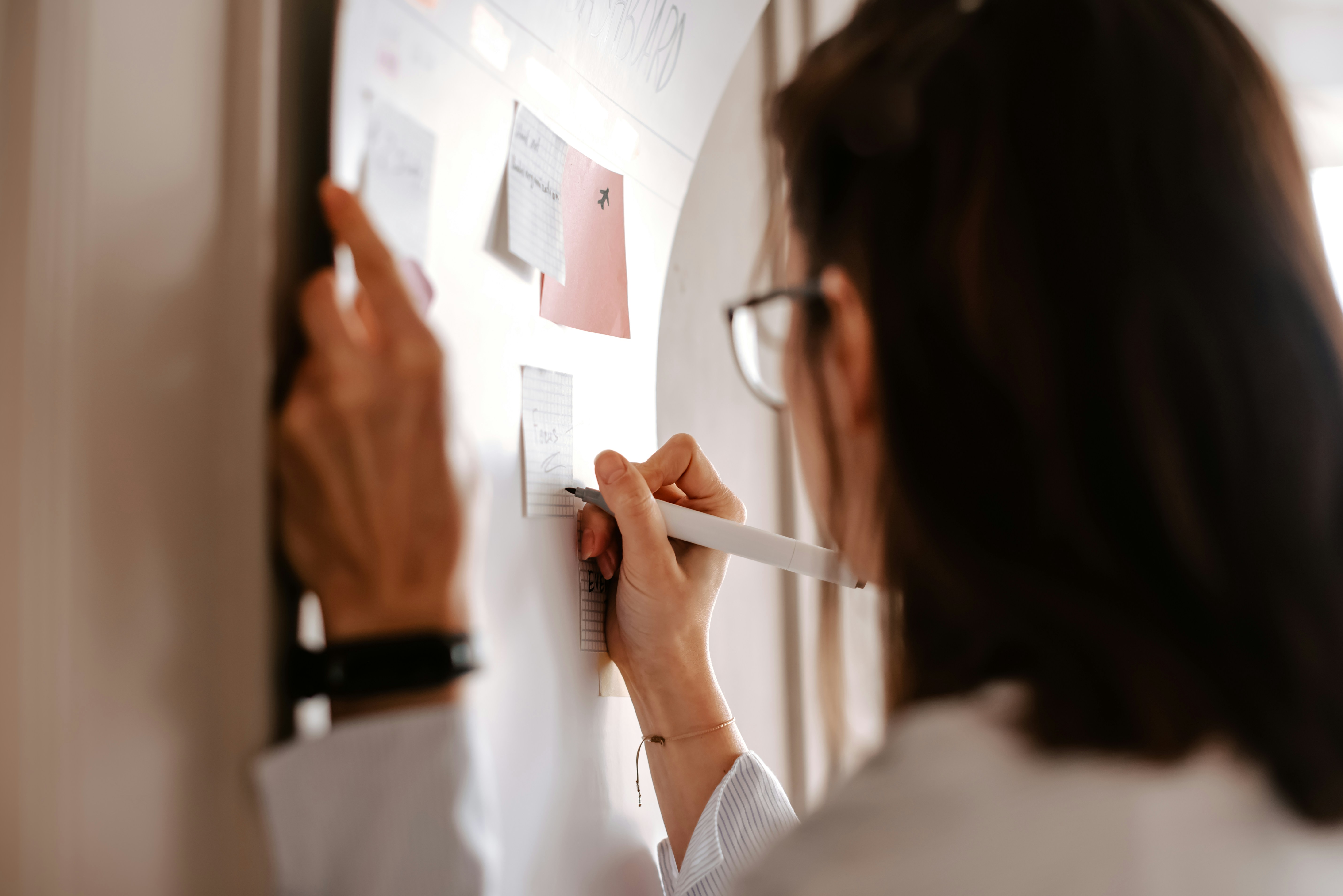 Person writing on a planning board with sticky notes